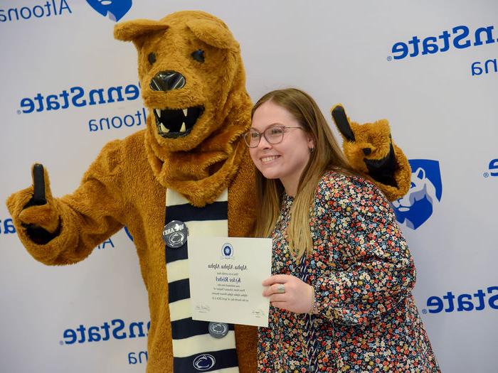 毕业于心理学专业的凯莉·瑞舍尔在毕业典礼后与她的证书和尼塔尼狮子合影留念. 